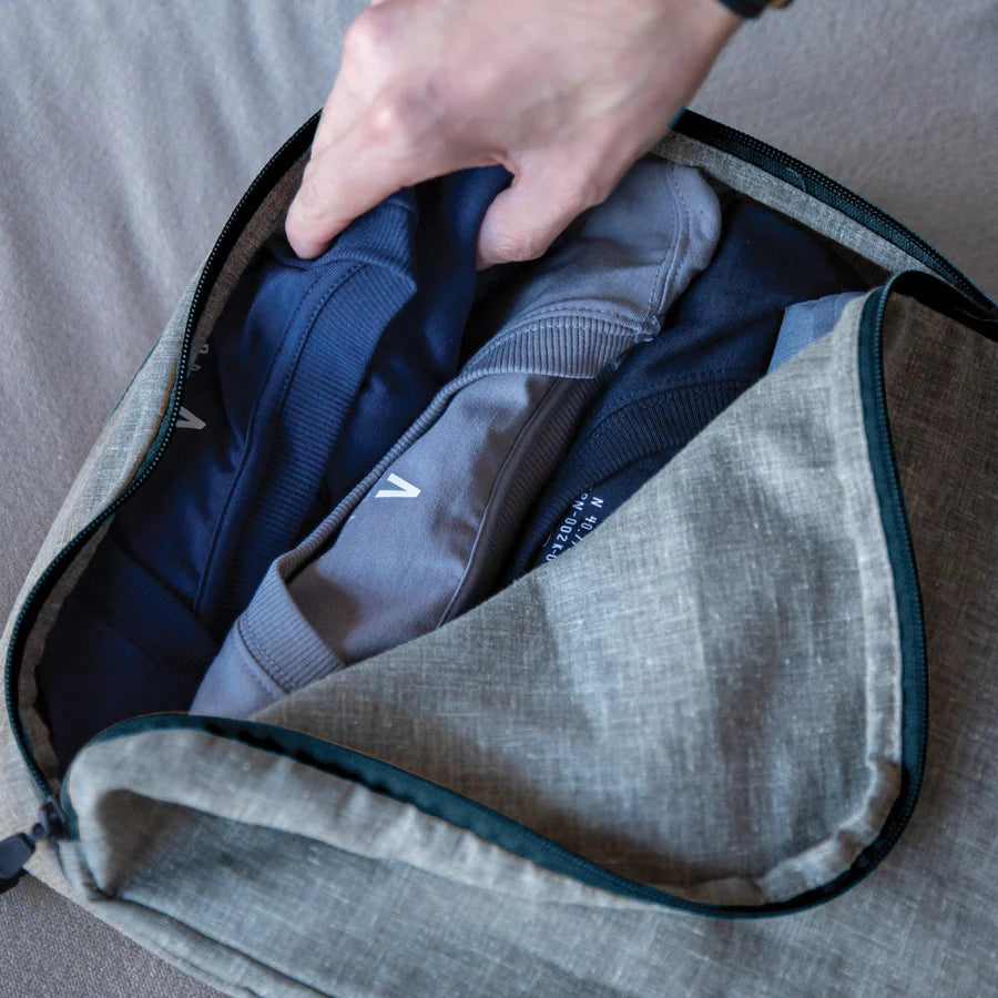 A man pulling out a folded shirt from his Hemp Cube