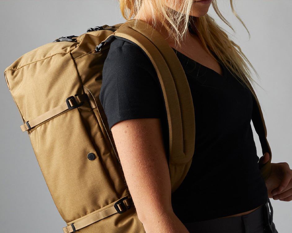 A young woman poses with a Boundary Supply Backpack.